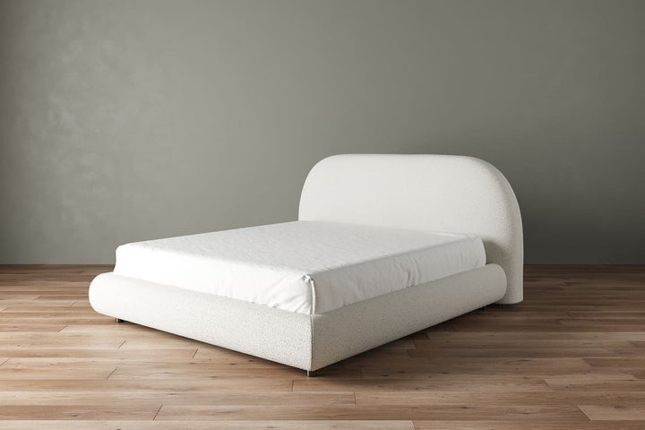 White bed frame with mattress on a wooden floor against a gray wall