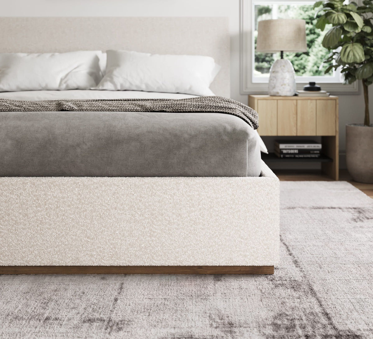 Modern bedroom with a gray upholstered bed and wooden nightstand.