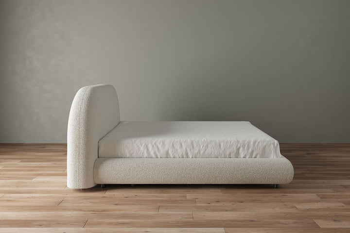 Beige bed with white mattress against a plain wall