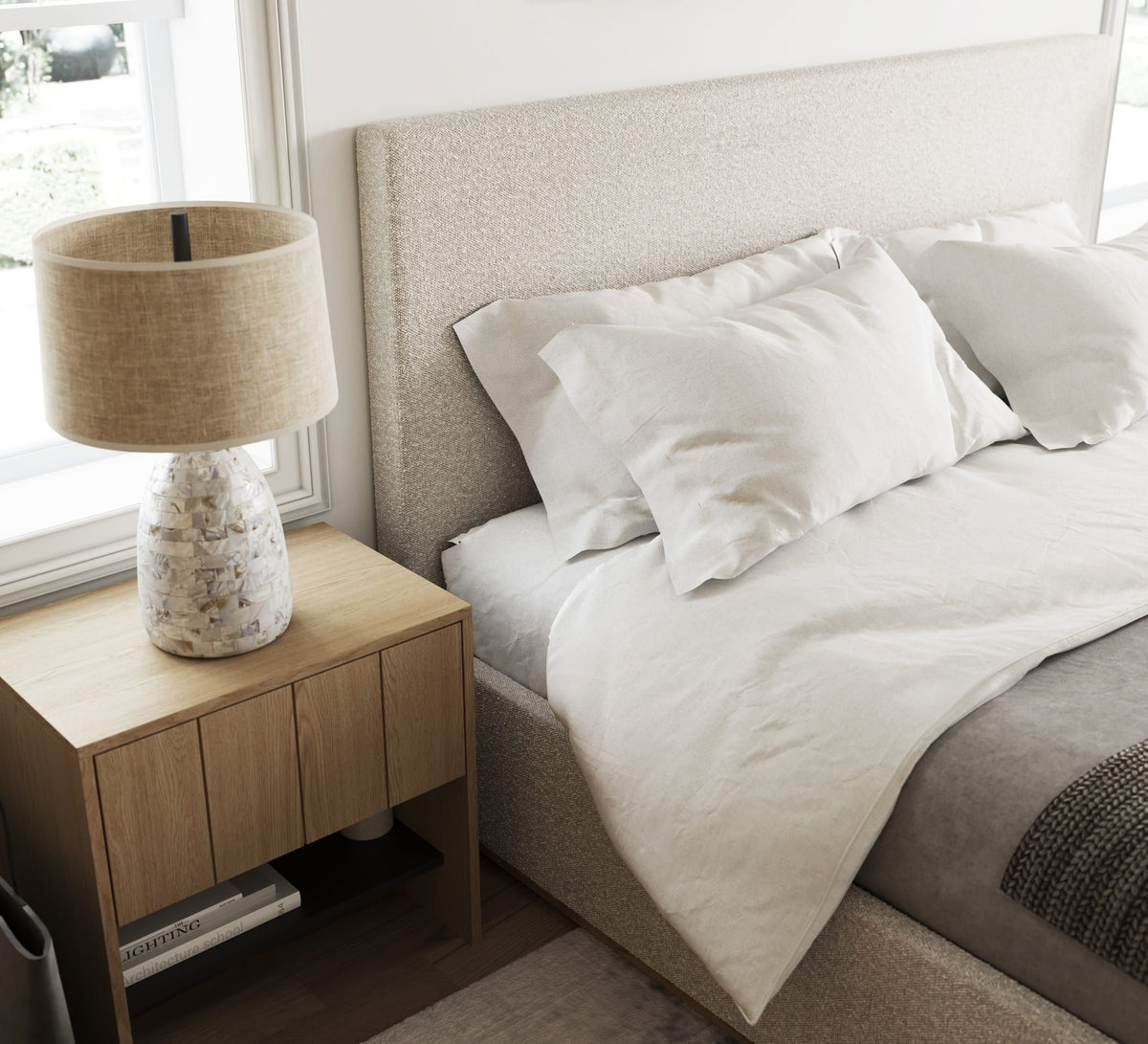 Neatly made bed with pillows and a lamp on a nightstand in a bedroom.