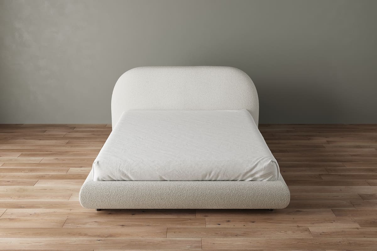 White bed on a wooden floor with a gray wall background