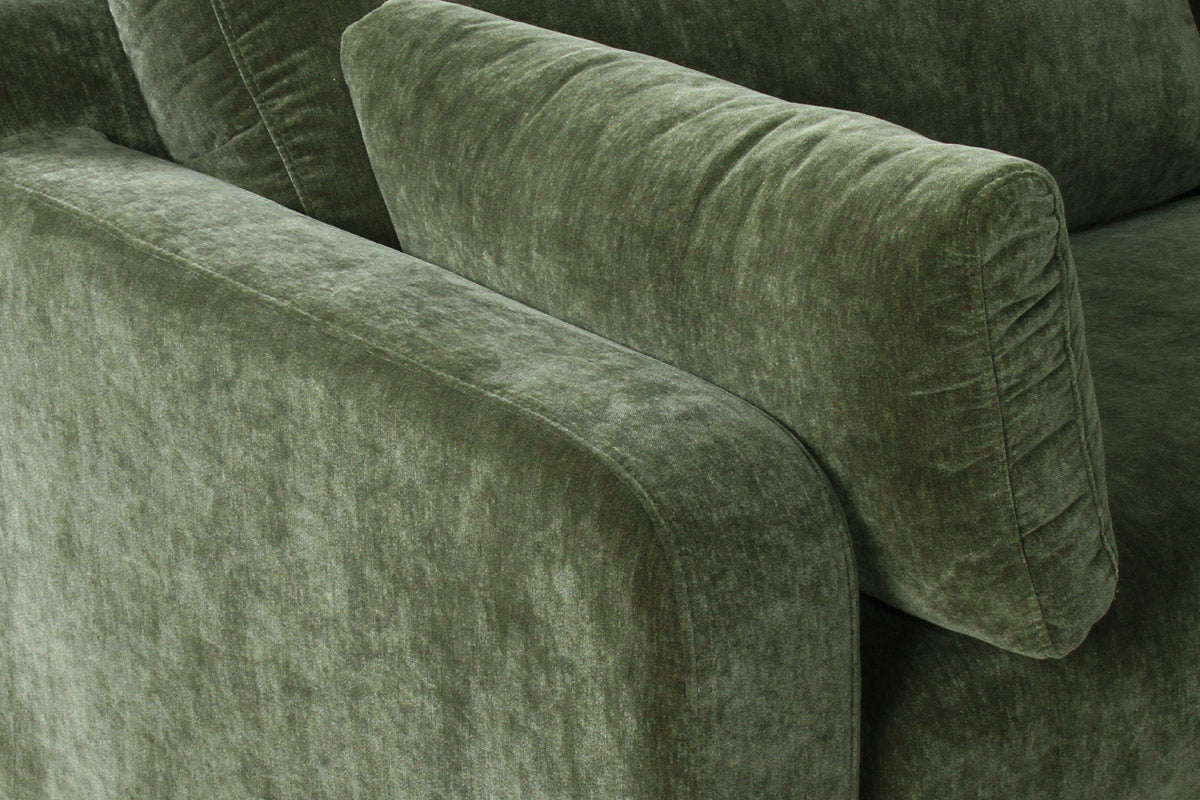 Close-up of a green velvet sofa with a textured surface.