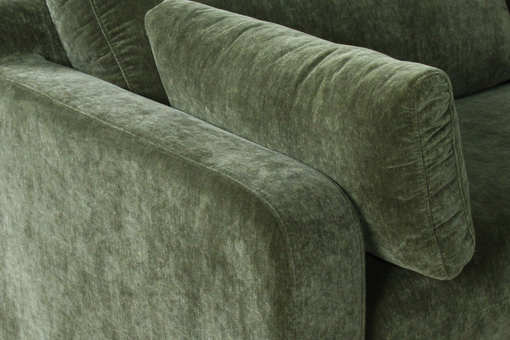Close-up of a green velvet sofa with a textured surface.