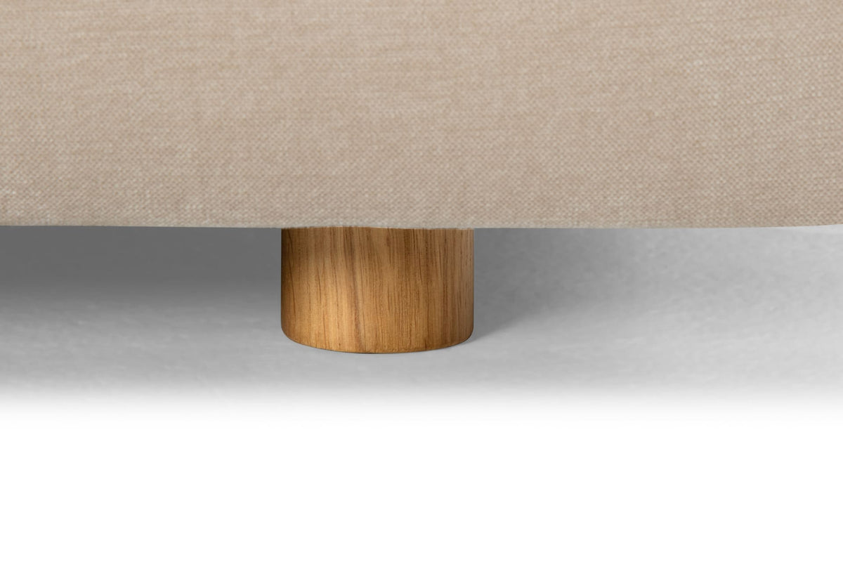 Close-up of a beige upholstered chair with a wooden leg on a light gray background