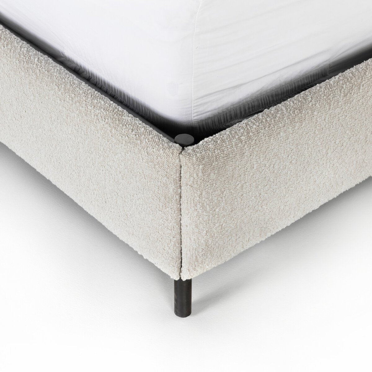 Anderson Bed Close-up of a textured bed frame corner with a white mattress.