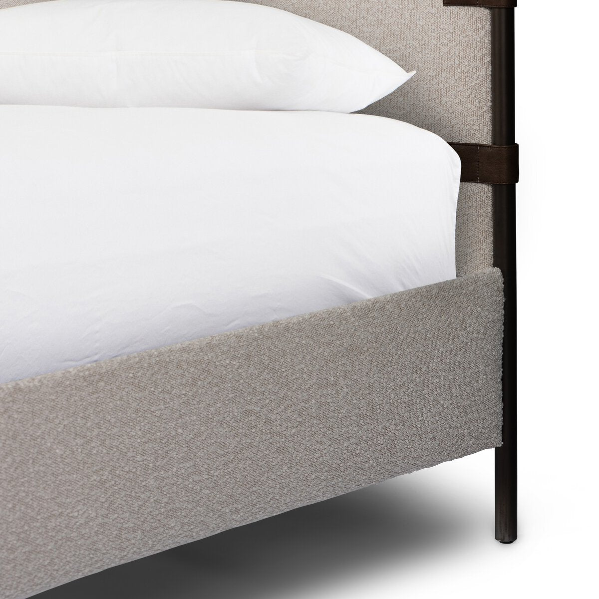 Gray upholstered bed with white bedding and a dark metal frame.