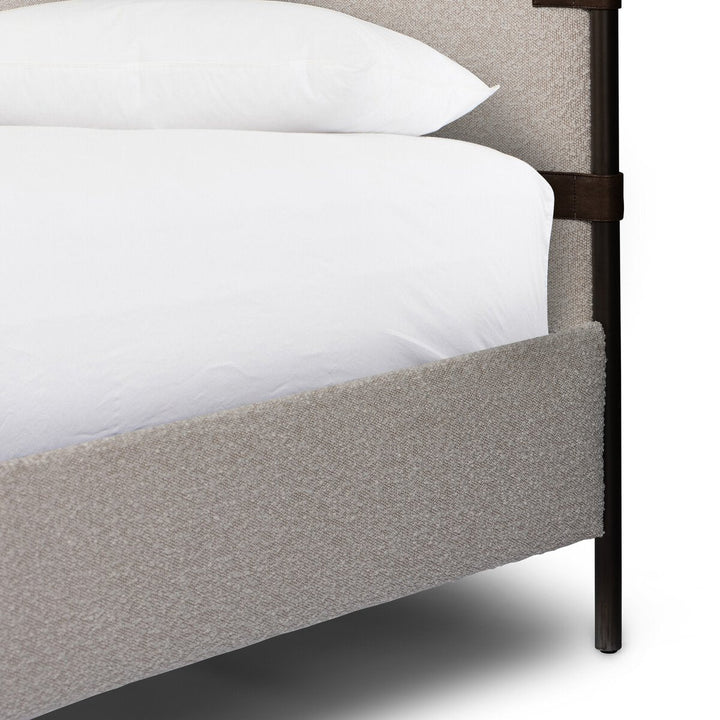 Gray upholstered bed with white bedding and a dark metal frame.