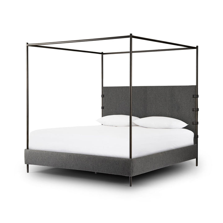 Canopy bed with gray upholstered headboard and white bedding on a white background