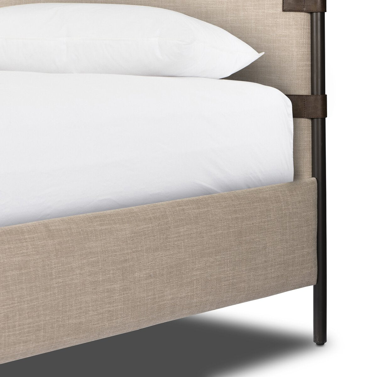 Beige upholstered bed frame with white bedding on a neutral background