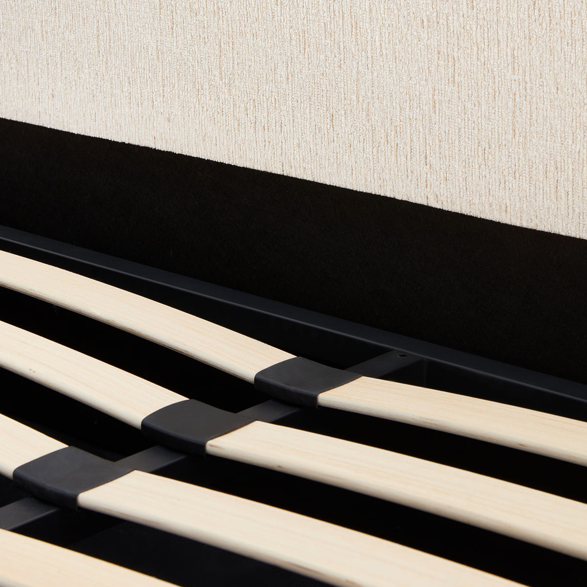 Close-up of a black and beige slatted headboard against a textured wall.