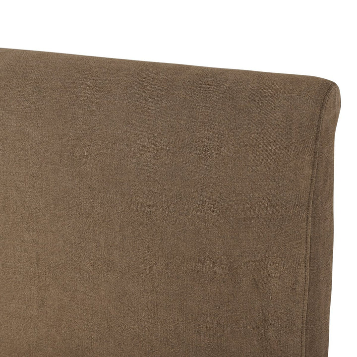 Close-up of a brown upholstered chair corner on a white background