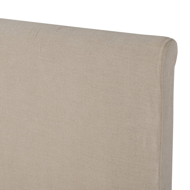 Close-up of a beige upholstered headboard corner on a white background