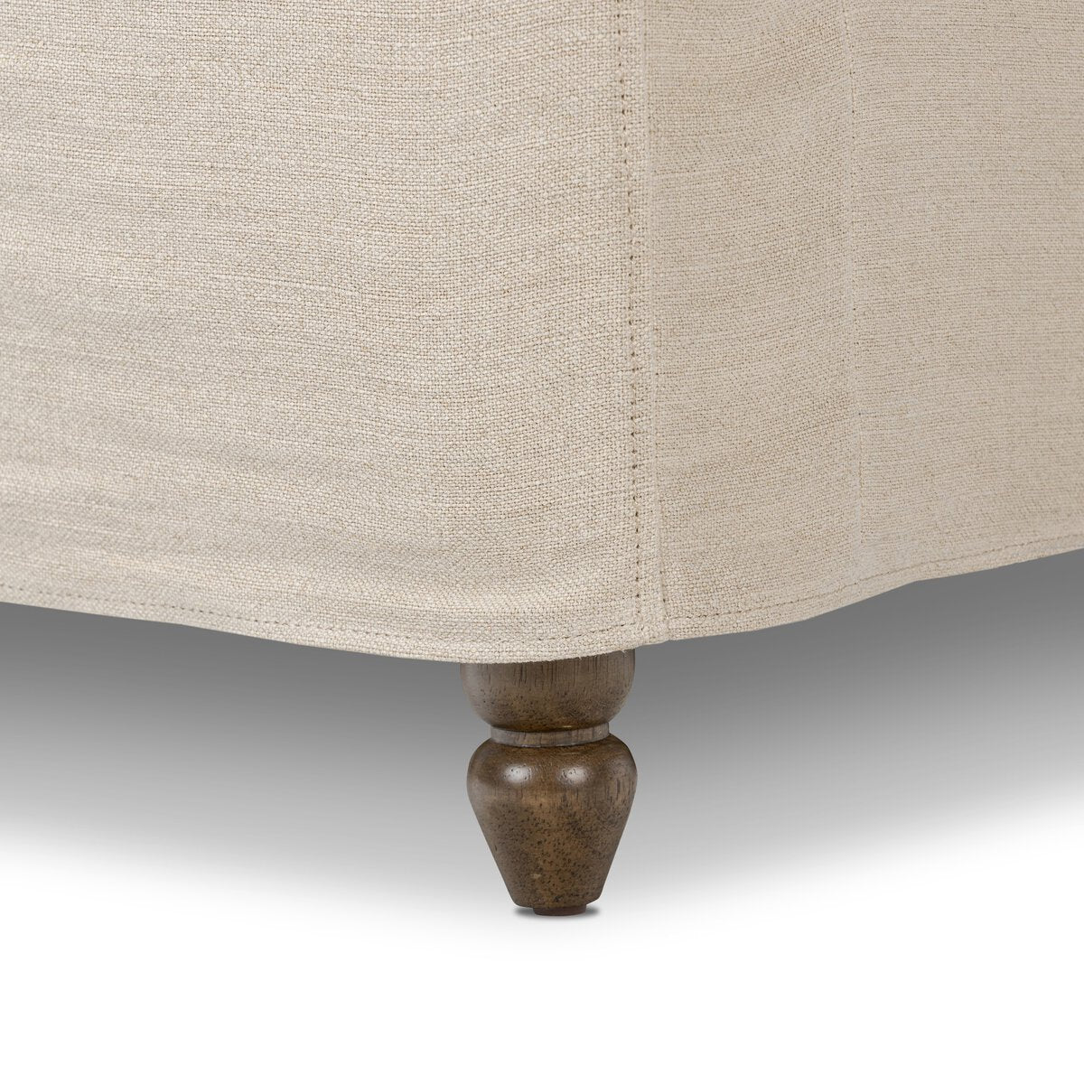 Close-up of a beige upholstered chair with a wooden leg on a neutral background