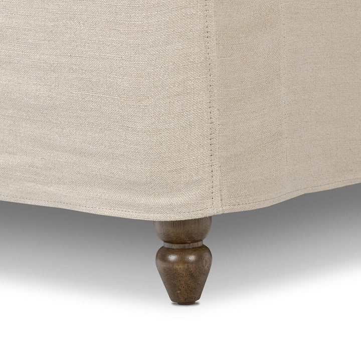 Close-up of a beige upholstered chair with a wooden leg on a neutral background