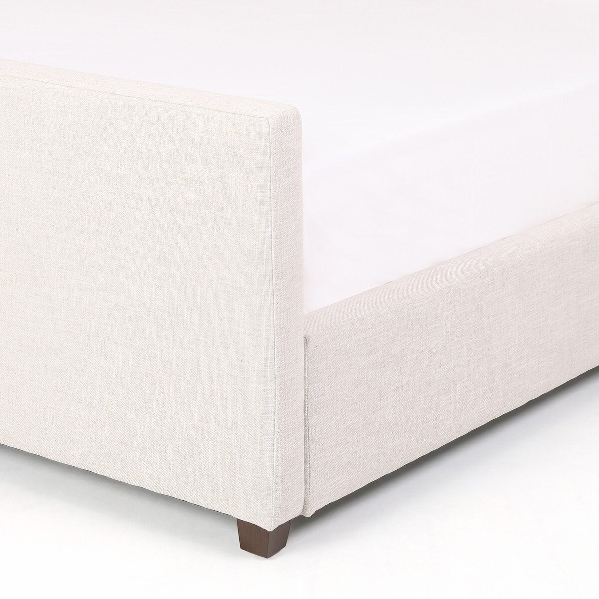 Corner of a light gray upholstered chair on a white background