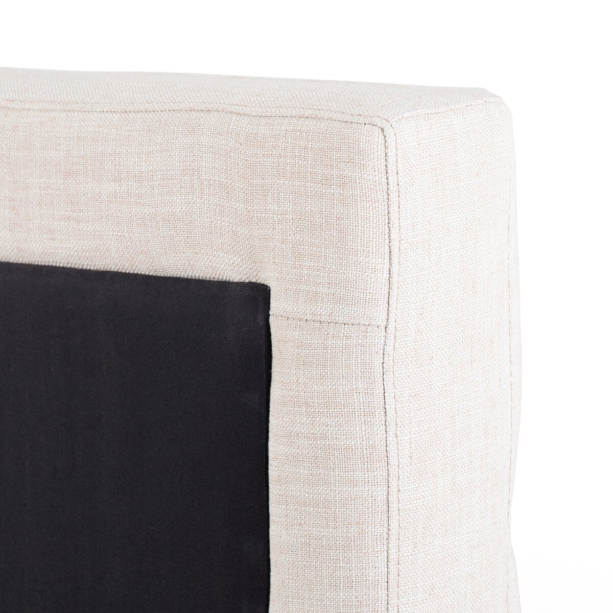 Close-up of a corner where a black cushion meets a beige fabric surface.