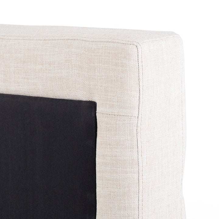 Close-up of a corner where a black cushion meets a beige fabric surface.