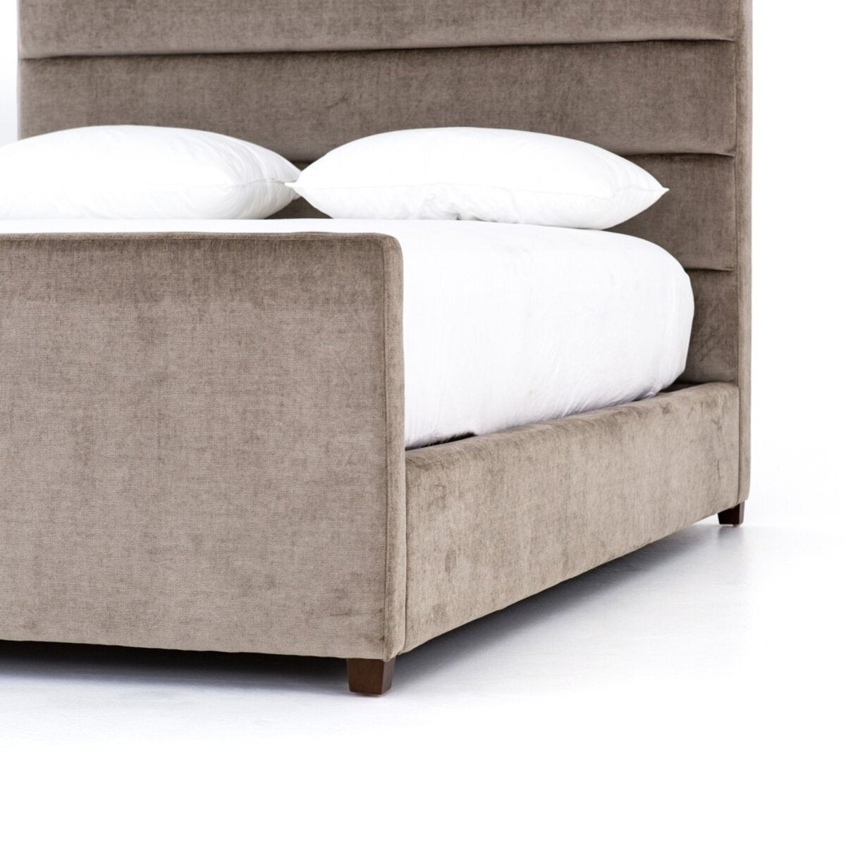 Beige upholstered bed with white bedding on a white background