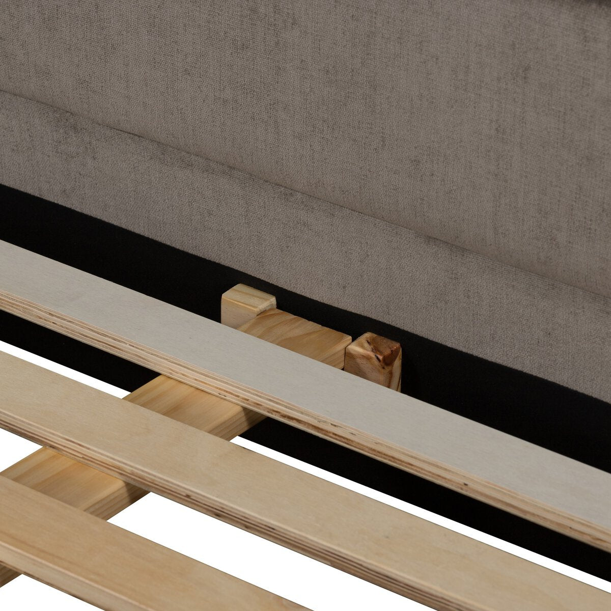 Wooden slats of a bed frame against a gray upholstered headboard.