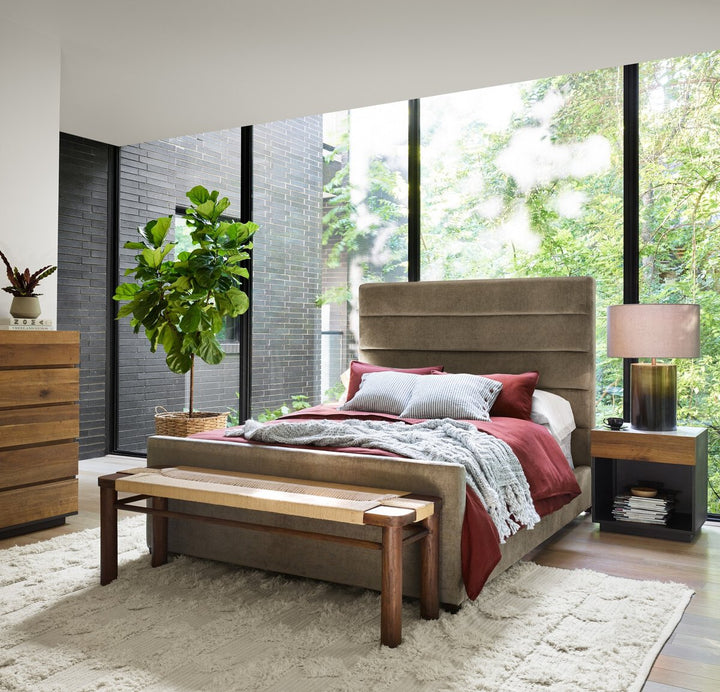 Modern bedroom with a large bed, wooden bench, and large windows.