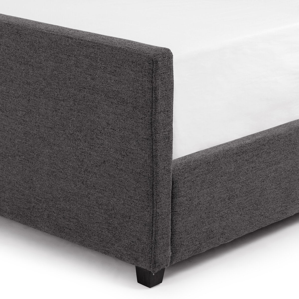 Gray upholstered bed frame corner on a white background