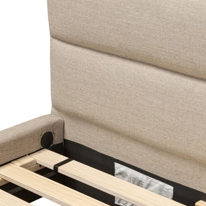 Close-up of a beige upholstered bed with wooden slats and a visible label.