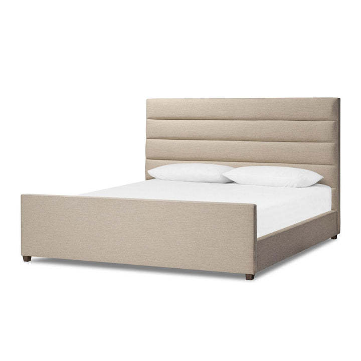 Beige upholstered bed with white bedding on a white background