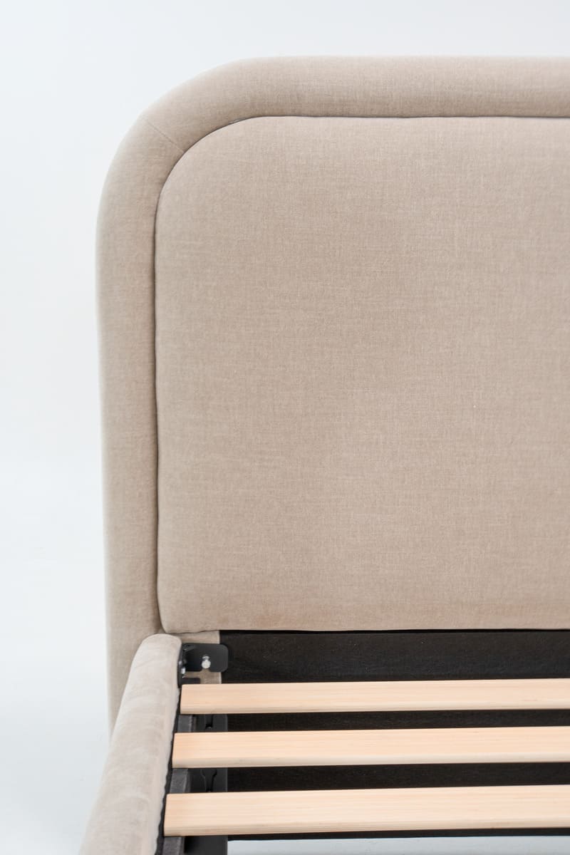 Beige upholstered bed frame with wooden slats on a white background