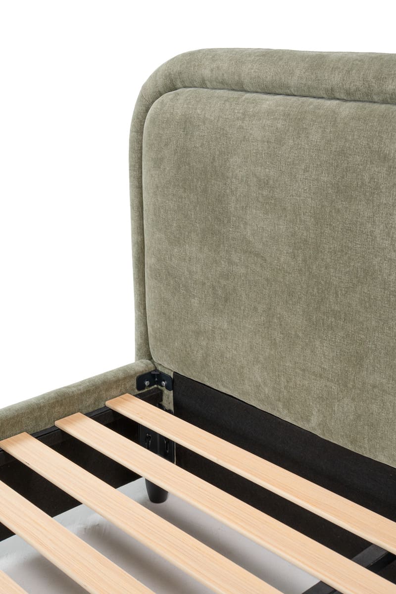 Close-up of a bed with wooden slats and a green upholstered headboard.