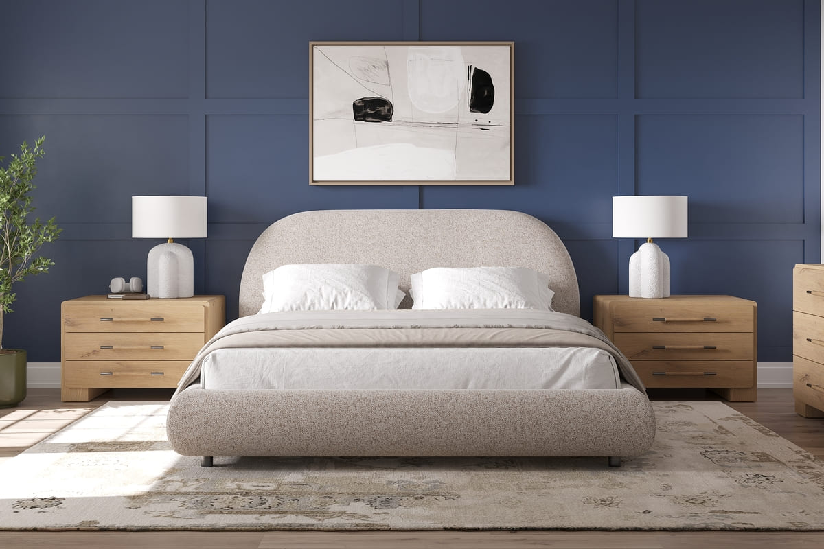 Beige upholstered bed in a bedroom with wooden nightstands and a framed picture on the wall.