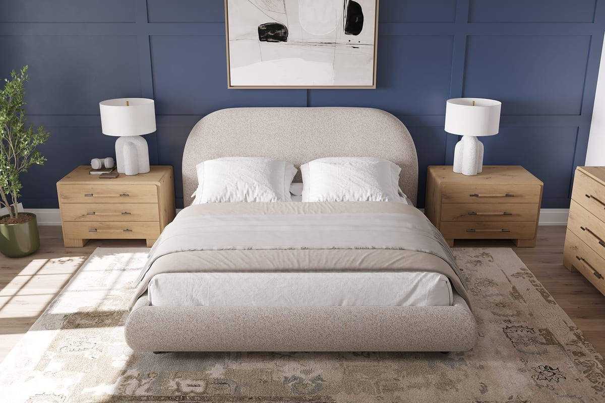 Neatly made bed in a bedroom with wooden nightstands, lamps, and decor.