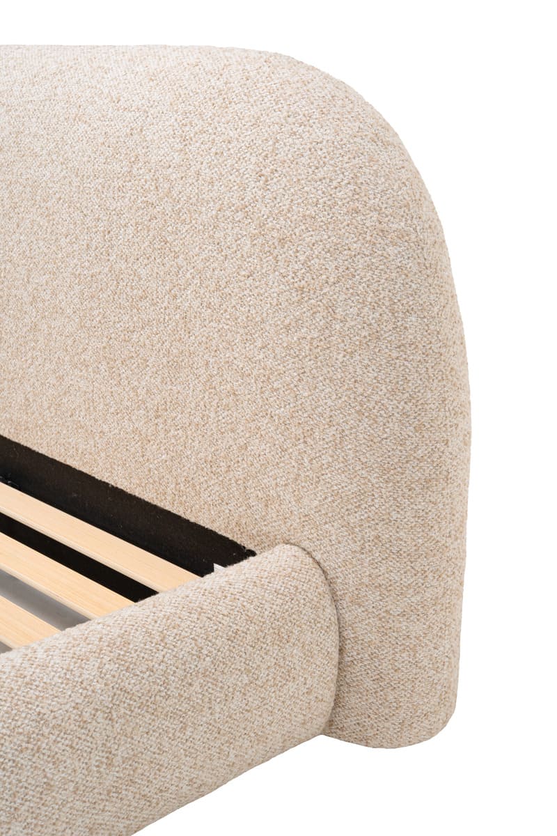Close-up of a beige upholstered headboard with wooden slats on a white background