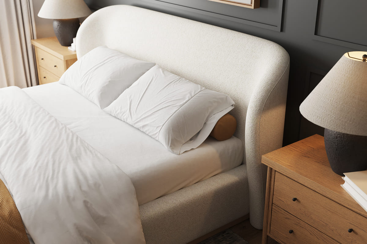White bed with pillows and a blanket in a bedroom setting.