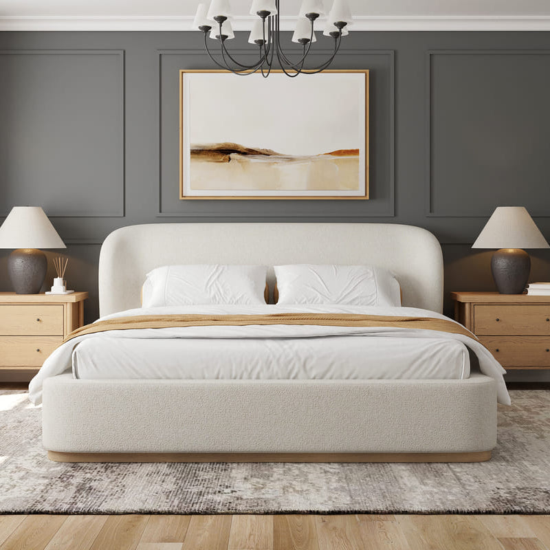 Modern bedroom with a beige upholstered bed, wooden nightstands, and abstract art on the wall.