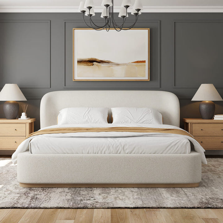 Modern bedroom with a beige upholstered bed, wooden nightstands, and abstract art on the wall.